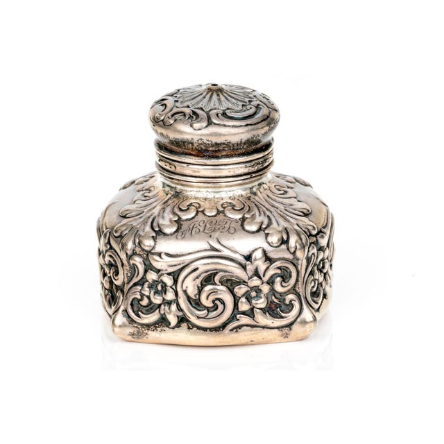 An ornate 19th century Rococò style inkwell consisting of intricate cast silver work mounted over a glass bottle by...