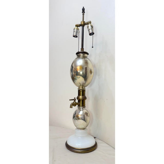 This large antique mercury glass, opaline glass, and brass seltzer dispenser electrified table lamp is a unique and...