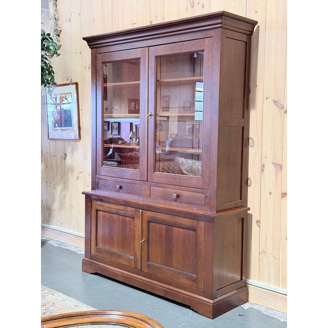 French walnut hutch cabinet crafted with a classic two piece design consisting of an upper glazed display cabinet and a...