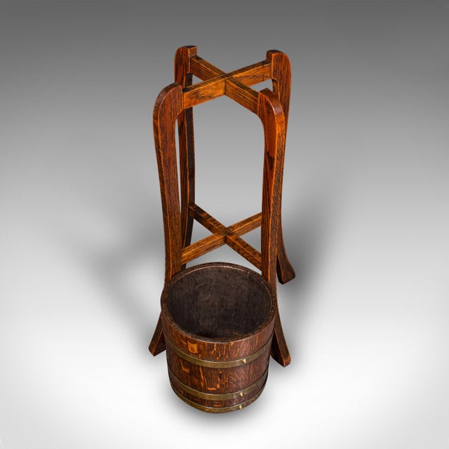 This is an antique coopered barrel jardiniere stand. An English, oak and brass planter, dating to the Edwardian period,...
