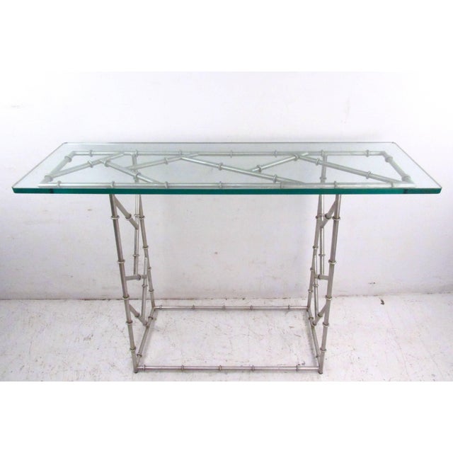 This faux bamboo console table features a sturdy metal frame base with glass top. Unique decorator's table offers a simple...