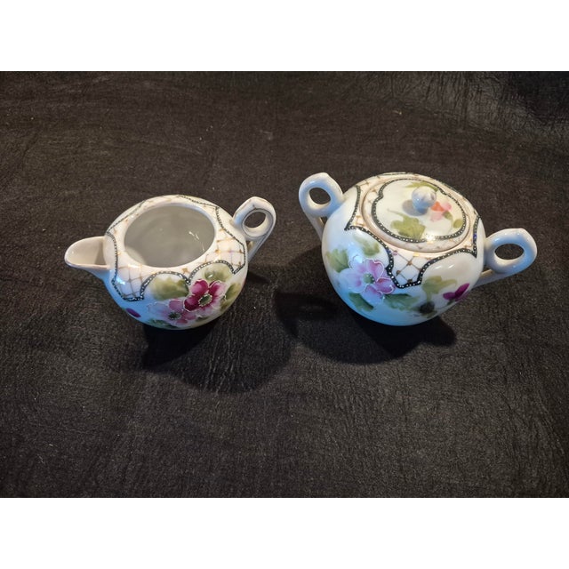 This vintage TE-OH China Nippon creamer and sugar bowl set features hand-painted pink floral designs with green foliage...