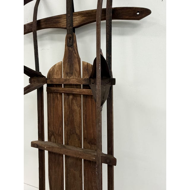 Vintage wooden snow sled with bentwood runners, slatted wood seat, and original rope pull. Finished in dark stained wood...