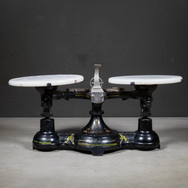 ABOUT A counter top mercantile or pharmacy balance scale having an enameled cast iron frame and dual milk glass trays....