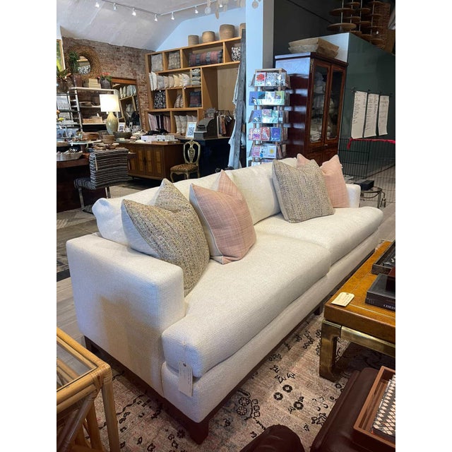 A contemporary sofa with track arms and an oak base. Memory-Down fill cushions upholstered in a crisp white woven fabric....