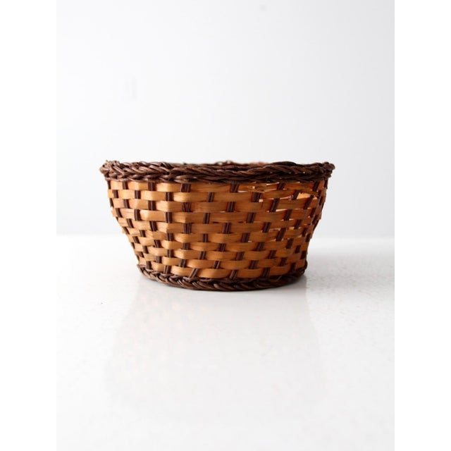 This vintage woven basket showcases a timeless two-tone design, featuring a tan body complemented by a dark brown base and...