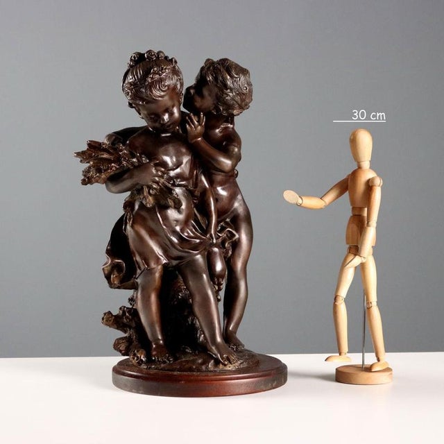 Bronze sculpture on a wooden base depicting whispering children. The base bears the artist's incised signature. Posthumous...