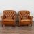 Pair of leather club chairs from Spain. Upholstered in vintage brown leather, the chairs feature tufted button backs, and...