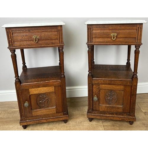 A beautiful pair of Antique French bedside tables featuring elegant marble tops and richly grained oak, showcasing classic...