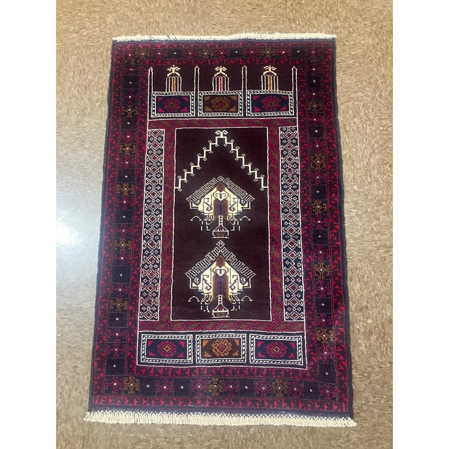Hand-knotted Baluch prayer rug, traditionally woven by tribal groups of eastern Iran and Afghanistan. Features a dark...