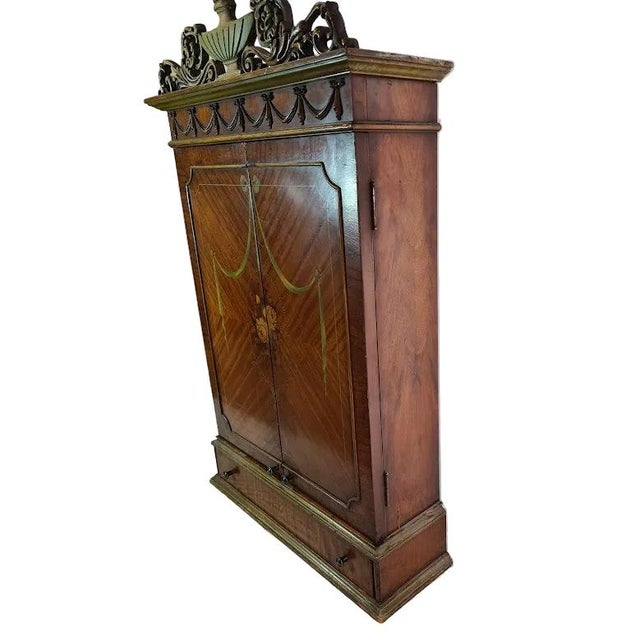 Antique wooden wall cabinet with a mirrored inside doors and back wall. Features ornate carved wooden scrollwork, festoon...