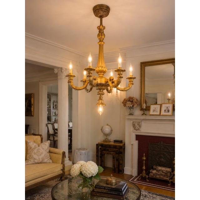 An elegant antique Louis XVI Revival chandelier featuring a richly carved giltwood frame, five scrolling candle arms, and...