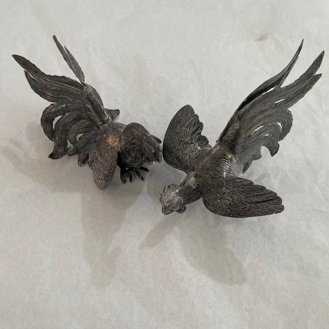 a silver-plated sculpture of a rooster or cockerel, likely part of a pair depicting fighting roosters. Silver plated...