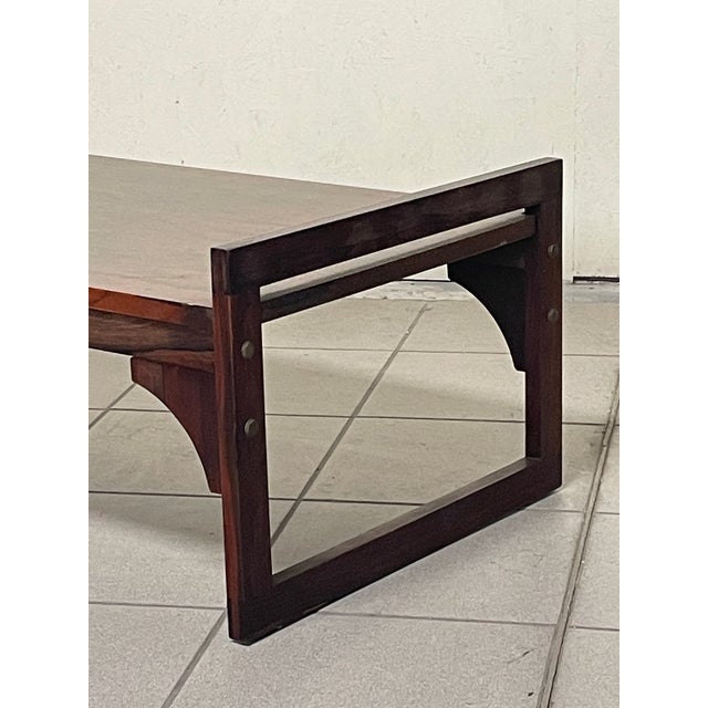 A 1960s coffee table made of fine rosewood, known for its dark, bold grain that creates a strong visual impact. It...