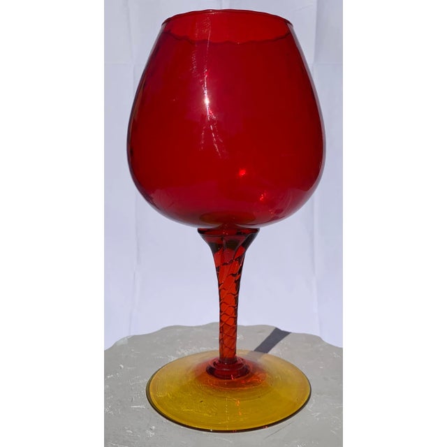 Large sized red whine glass. Circular base with yellow finish.