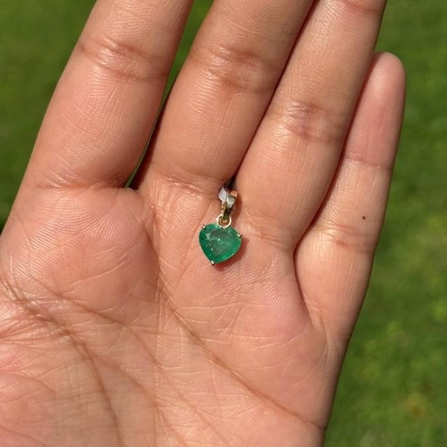 This heart shape solitaire pendant features a 1.45 carat emerald 14K yellow gold. The emerald measuring 7 x 8 mm in size...