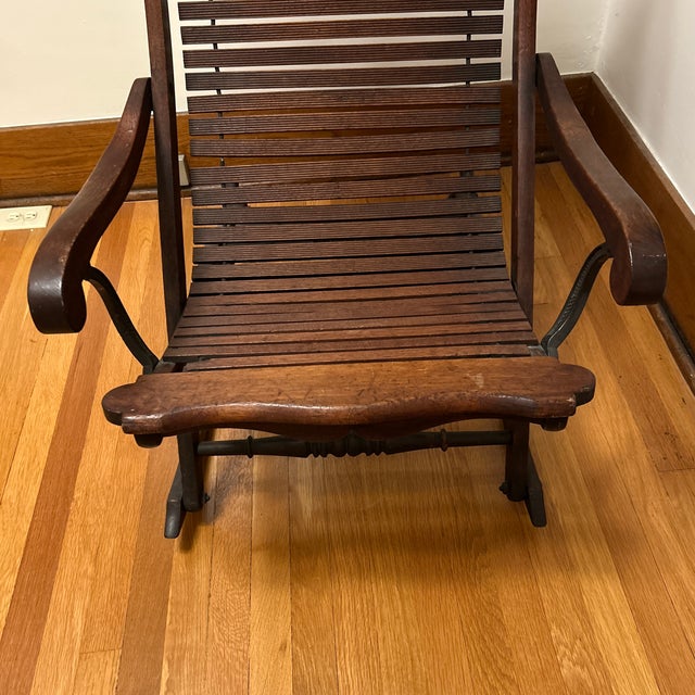 This is a stunning antique rocking chair featuring lo a rare style linked slat wood seat allowing the chair to adjust its...