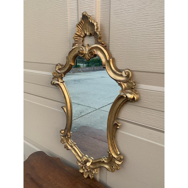 An Italian Rococo–style giltwood wall mirror, richly carved with scrolling acanthus and shell motifs that give the piece...