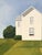 The Old Farmhouse by Justin Wheatley | Acrylic on Canvas White Farmhouse With Green Fields For Sale - Image 4 of 11