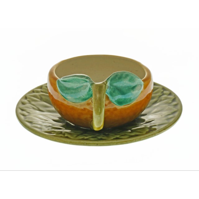 This charming French majolica cup and saucer is whimsically shaped like a ripe orange, complete with a sculptural twig-...