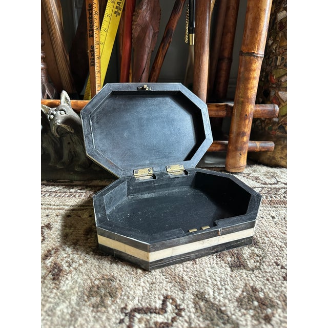 A striking vintage bone inlay box featuring a bold black and ivory geometric design across an octagonal form. The lid...