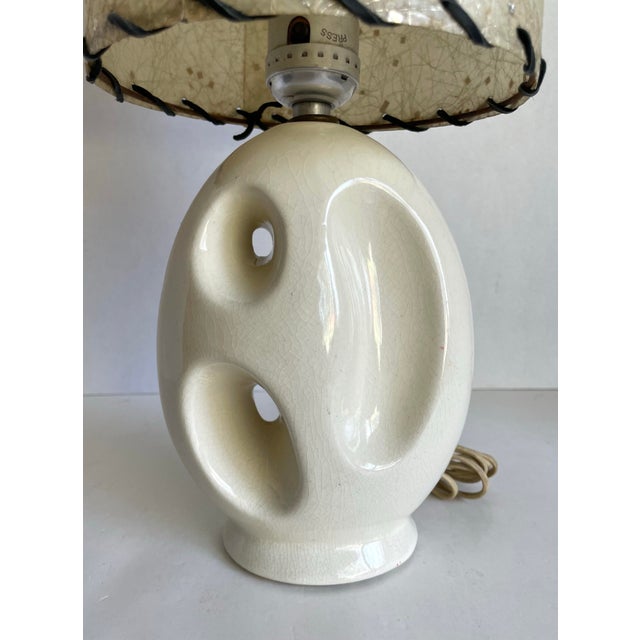 This sculptural ceramic table lamp, likely dating to the 1960s, features an organic oval base with dramatic biomorphic...