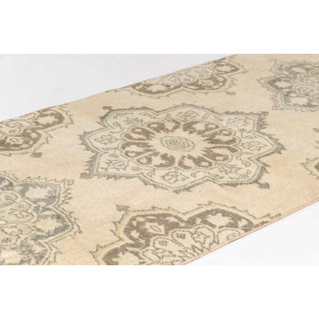 This is a vintage Turkish Oushak rug from the Mid 20th Century. The piece was hand-knotted.