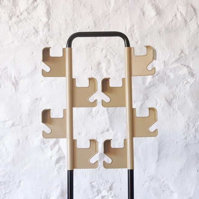 Two black lacquered steel axles support two sets of four beige plastic hooks for hanging clothes or hats. Being 360-degree...
