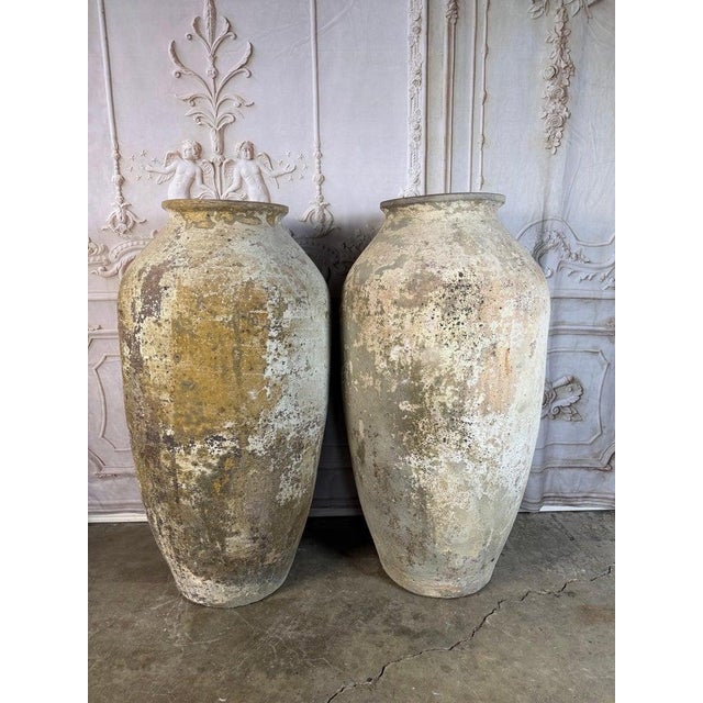 An impressive pair of monumental terracotta olive jars, celebrated for their generous scale and beautifully worn surfaces....