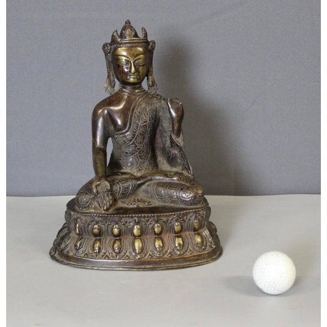 Bronze Buddha seated on a lotus flower, origin Nepal, late 19th century, note one finger is missing