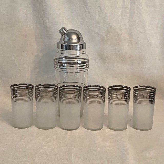 6 frosted glasses with platinum rings around the rims with matching cocktail shaker. The shaker has a frosted base and...