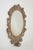 French Provincial style wood wall mirror framed with carved scrolling foliage and acanthus leaves. There is a small cup...