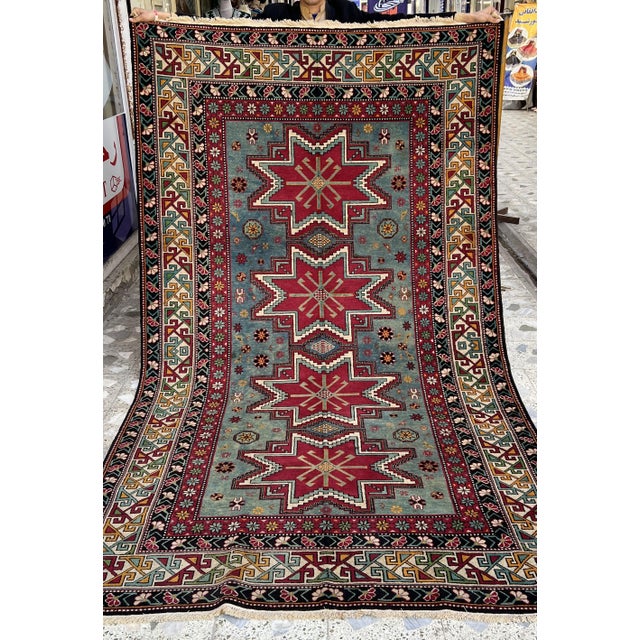 Caucasian Shirvan design hand-knotted rug featuring four bold eight-pointed Lesghi star medallions in crimson with crisp...