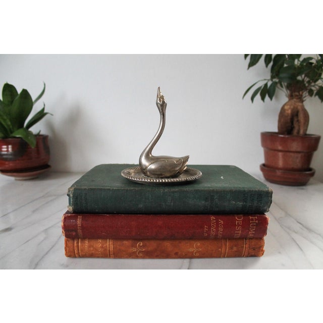 Vintage silver-plated metal swan ring holder and trinket dish, featuring an embossed floral design with a roped edge on...