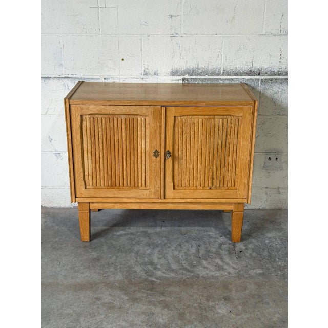 This compact storage cabinet features double doors opening to an interior shelf for organized storage. Textured reeded...
