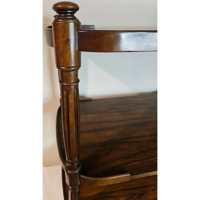 A mid-20th century Baker Furniture bar cart in richly figured rosewood with brass casters and hardware. Three generous...