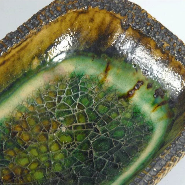 Brutalist platter made of raw ceramic, decorated with thick, cracked glaze resembling a sheet of ice. It comes from the...