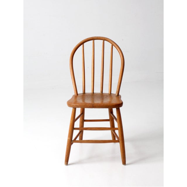 Classic vintage Windsor-style chair with a gracefully curved hoop back, turned spindle details, and a shaped wood seat...