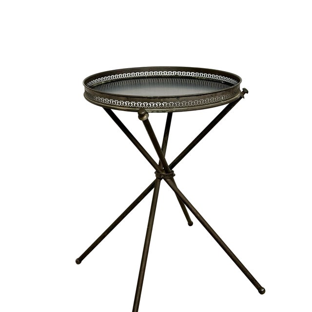 A distinctive vintage folding cocktail table combining a delicate architectural base with an ornate round tray-form top....