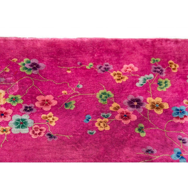 An incredible early 20th century Chinese Art Deco rug with a fucshia ground overlaid with multi-colored flowers and...