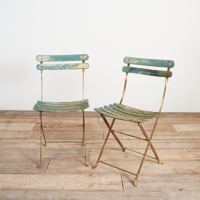 A pair of classic French slatted folding garden chairs. The wooden slats are in their original green/white paint with a...