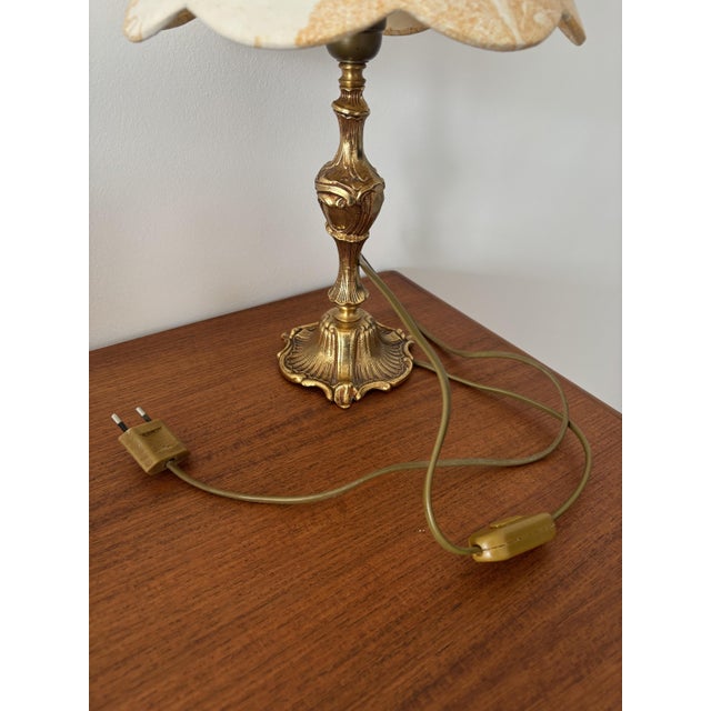 An elegant table lamp with antique charm, featuring a beautiful ecru lampshade decorated with a landscape motif in ochre...