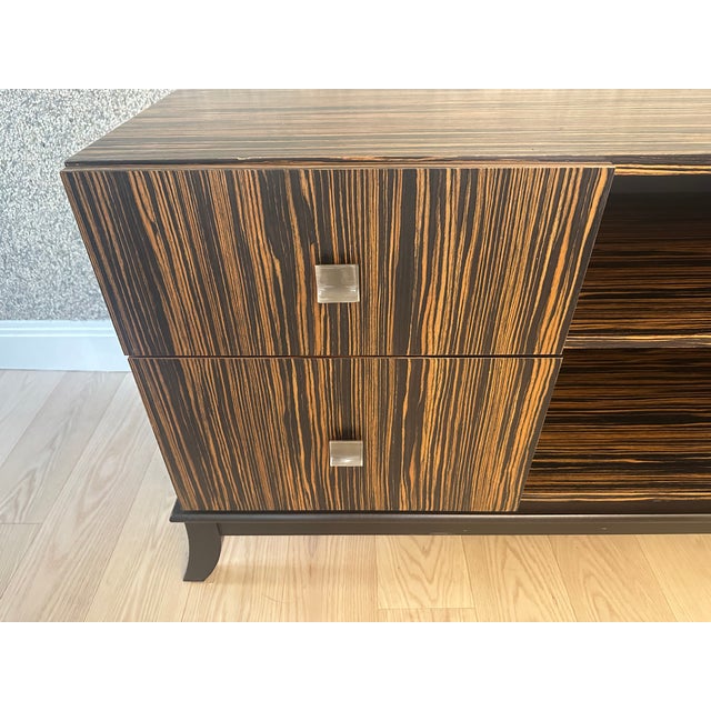 This contemporary macassar ebony console has versatile open center shelves with two drawers on each side, brushed silver...
