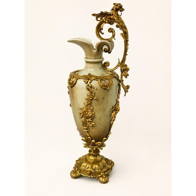 An exceptional pair of decorative jugs crafted from ceramic and richly adorned with mercury-gilt bronze (ormolu) mounts,...