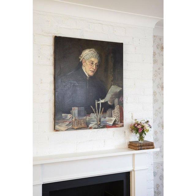 A striking and deeply atmospheric antique oil portrait dated 1903, capturing an elderly woman seated at her writing table,...