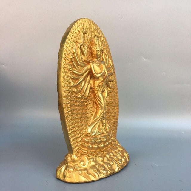 Ornate standing sculpture of Thousand-Armed Avalokiteshvara, crafted from brass with gilded finish. The figure stands atop...