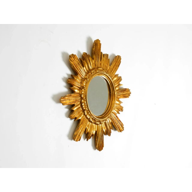Beautiful Italian mid-century sunburst wall mirror made of gilded wood and resin. Great 1950s design. No damage to the...