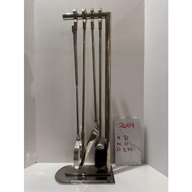 Eichholtz Ennell fireplace set with four tools: brush, tongs, poker, and shovel, plus coordinating stand. Polished nickel...