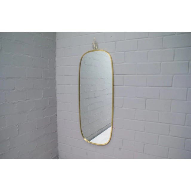 This very nice, solid and large wall mirror was produced in the 1950s. The mirror itself has a height of about 118cm and a...