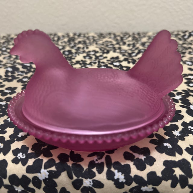 This hen on nest features a frosted purple finish with detailing on the feathers and a beaded edge base.